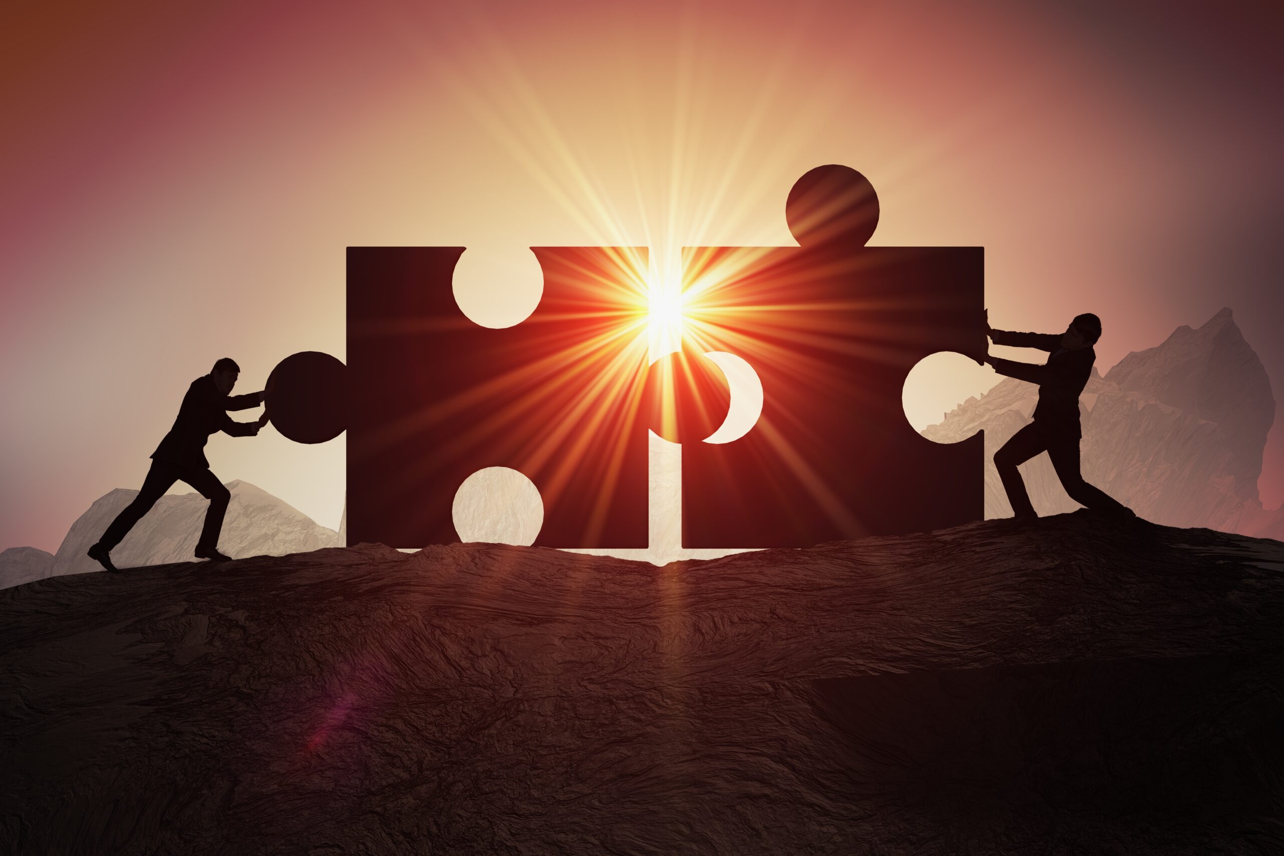 Teamwork, partnership and cooperation concept. Silhouettes of two businessman joining two pieces of puzzle together.